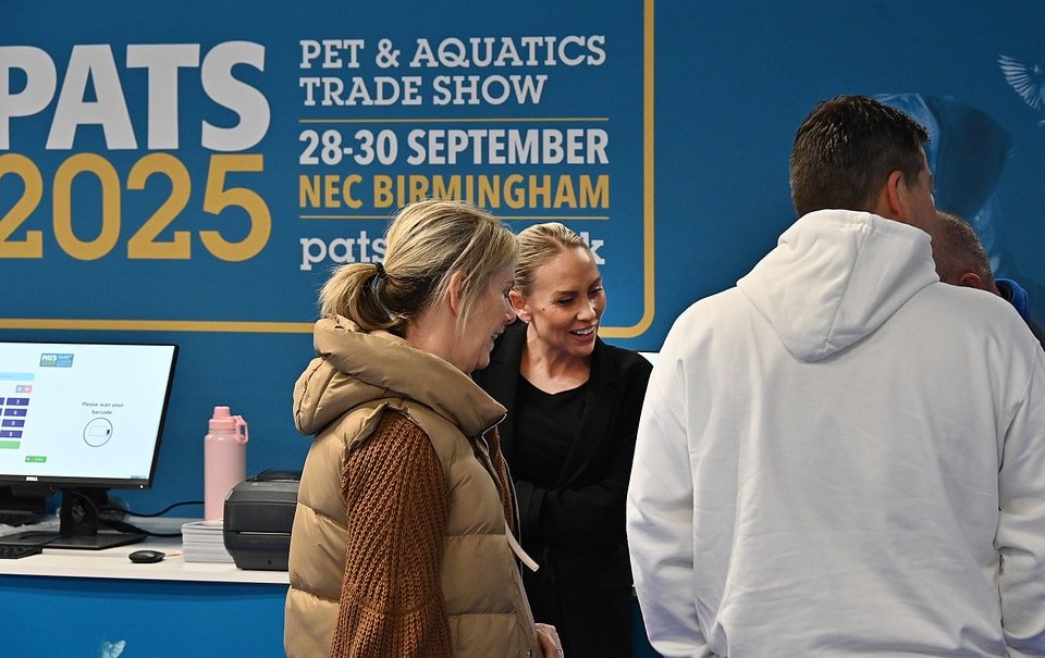 Crowded exhibition hall at PATS 2025 held at NEC Birmingham, showcasing pet and aquatics product booths, live grooming demos, and international visitors networking across colorful brand displays.